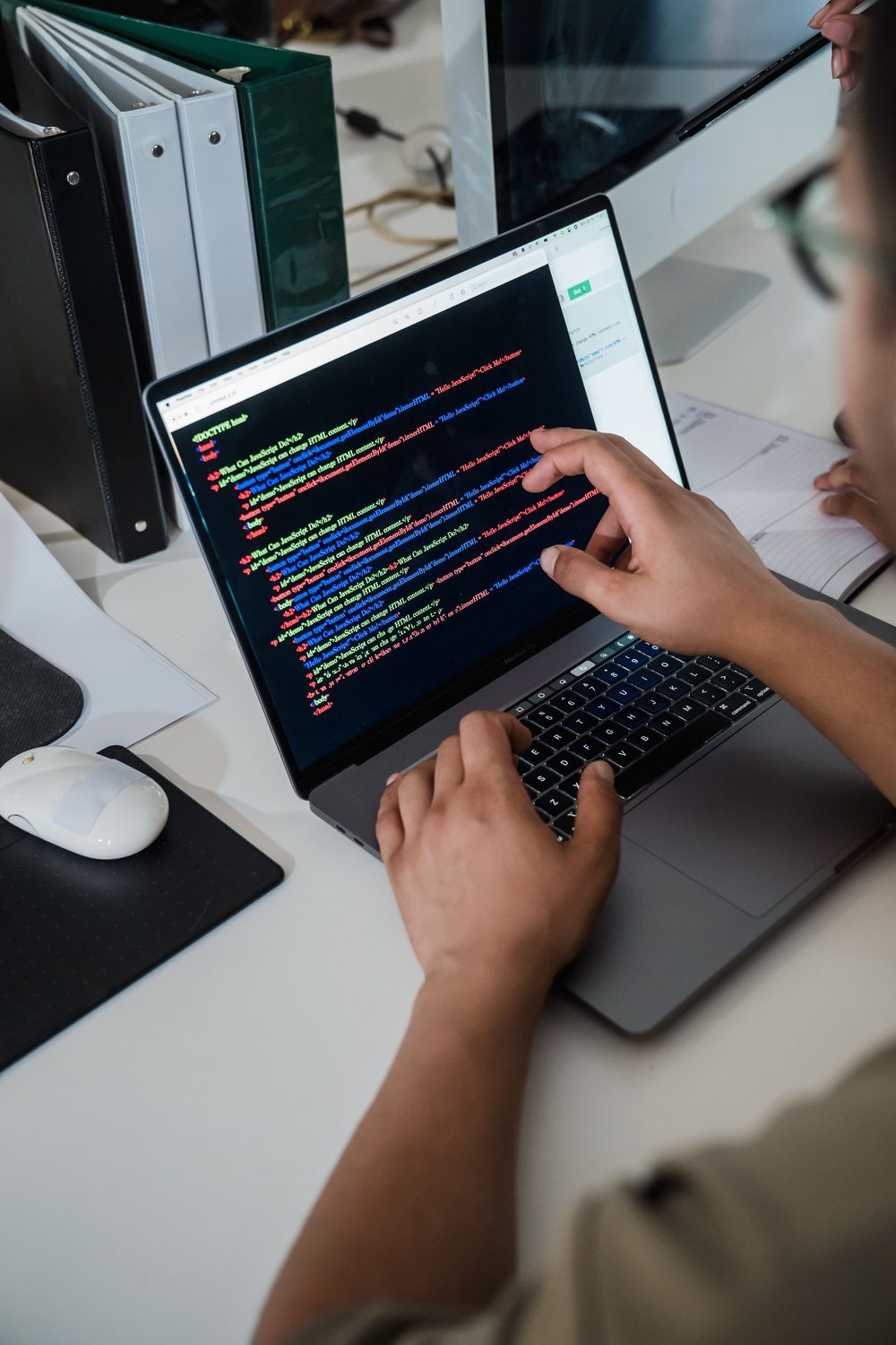 A developer pointing at code on a laptop screen